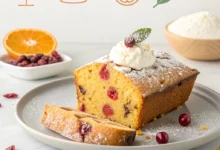 Sliced cranberry orange loaf cake with orange glaze, fresh cranberries and orange slices