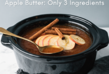 Thick, spiced slow cooker apple butter in a jar with fresh apples nearby, a featured homemade autumn recipe.