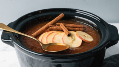 Thick, spiced slow cooker apple butter in a jar with fresh apples nearby, a featured homemade autumn recipe.