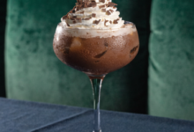 Two chocolate martinis in stemmed glasses, garnished with chocolate shavings and a raspberry.