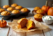 Golden cottage cheese pumpkin muffins in a baking pan with a split muffin showing the soft orange crumb