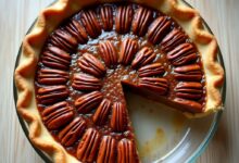 Classic pecan pie with glossy filling and pecan halves in a glass pie dish, one slice removed