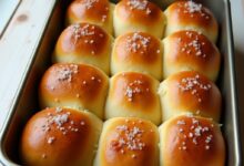Golden soft pull-apart dinner rolls brushed with butter in a 9x13 baking pan